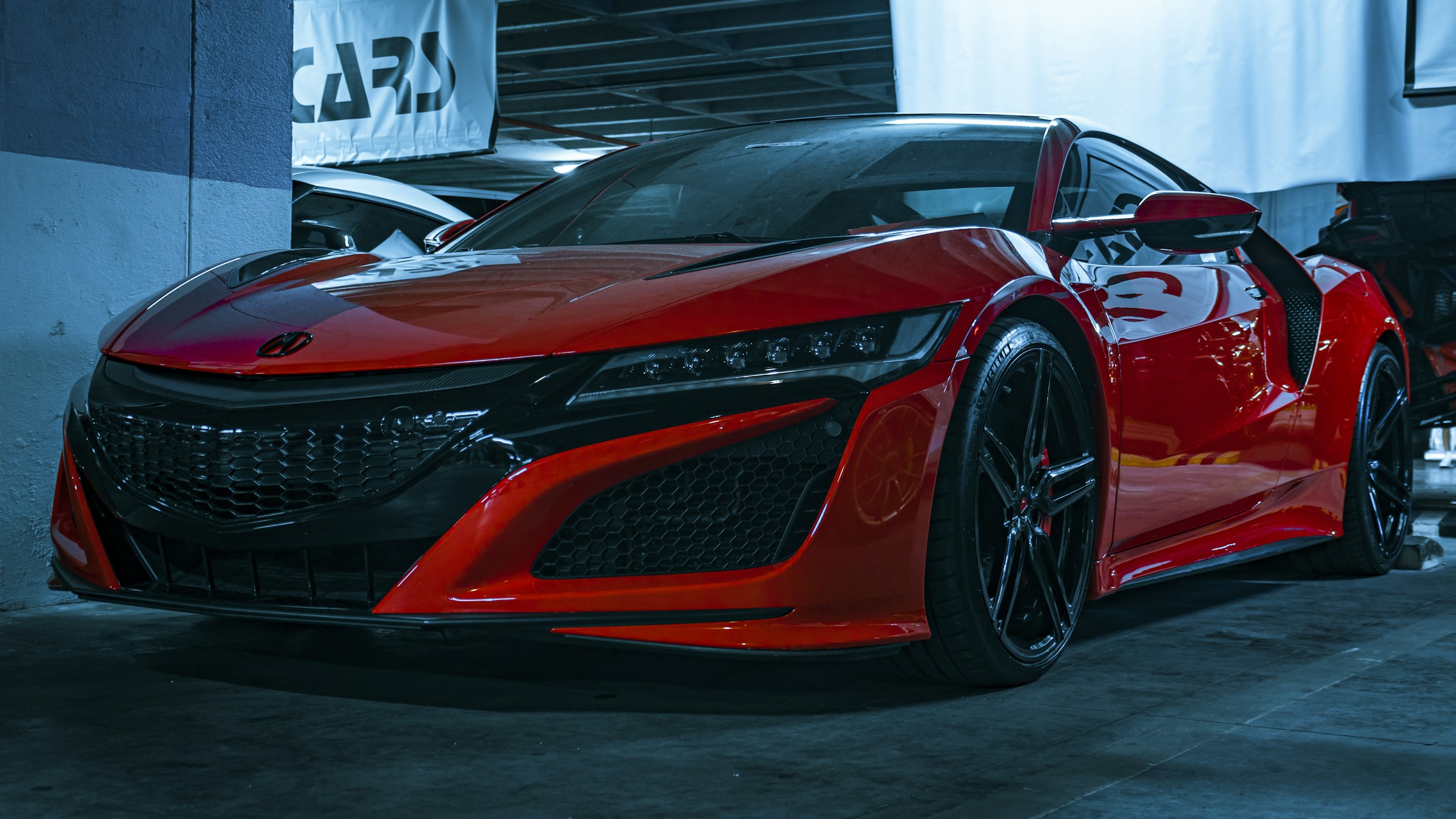 Red second-generation Acura NSX in a dark showroom