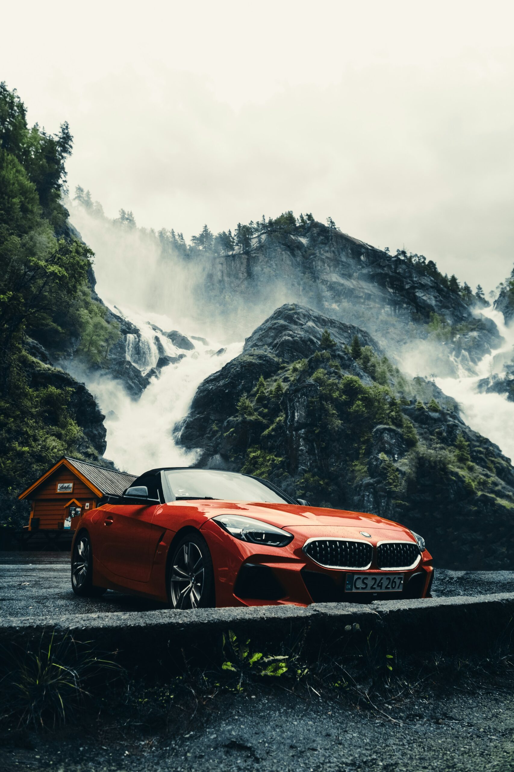 Red BMW Z4 G29 roadster before a mountain waterfall