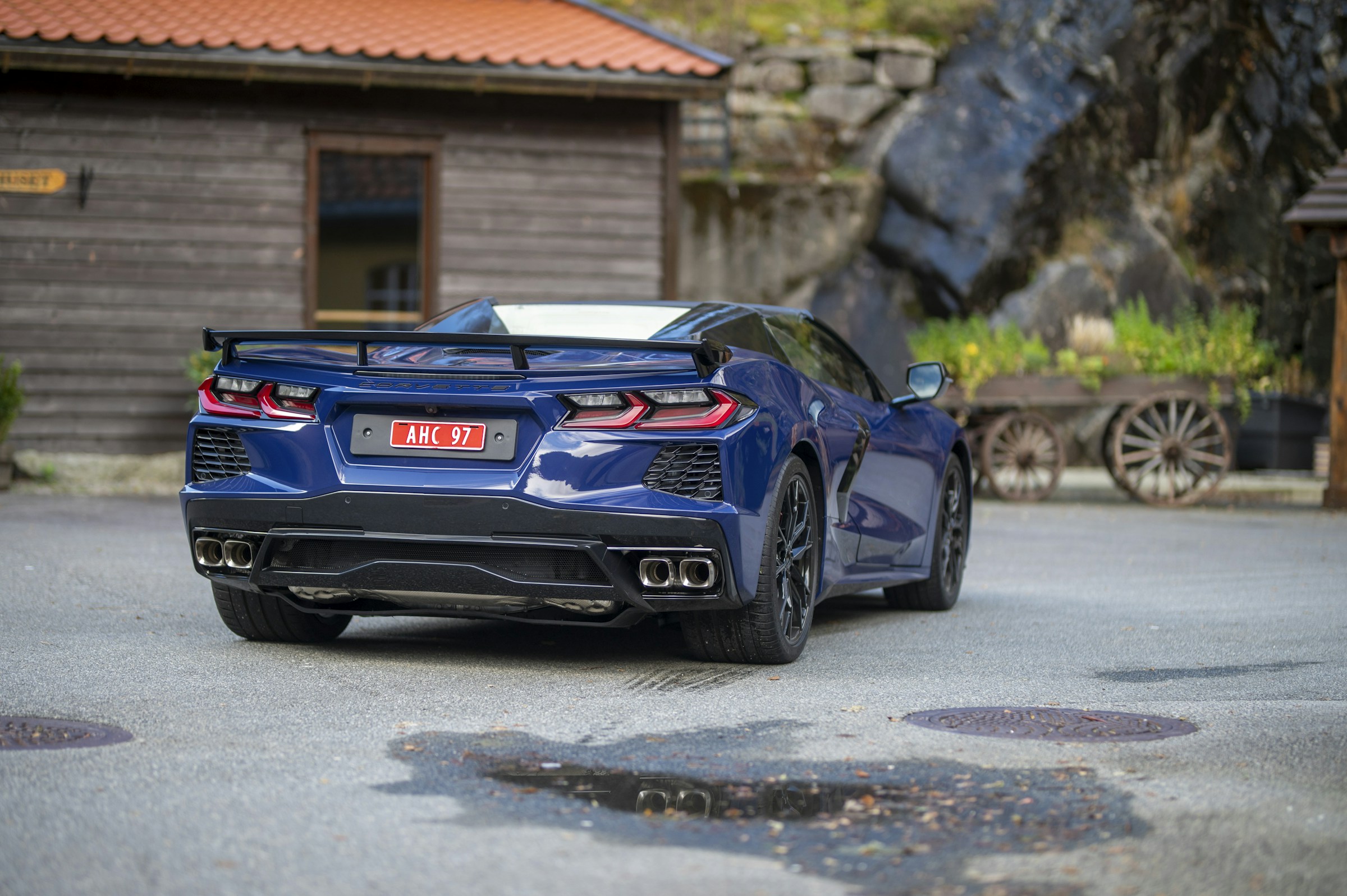 Blue Chevrolet Corvette C8 Stingray convertible, rear three-quarter view with the factory high-wing spoiler