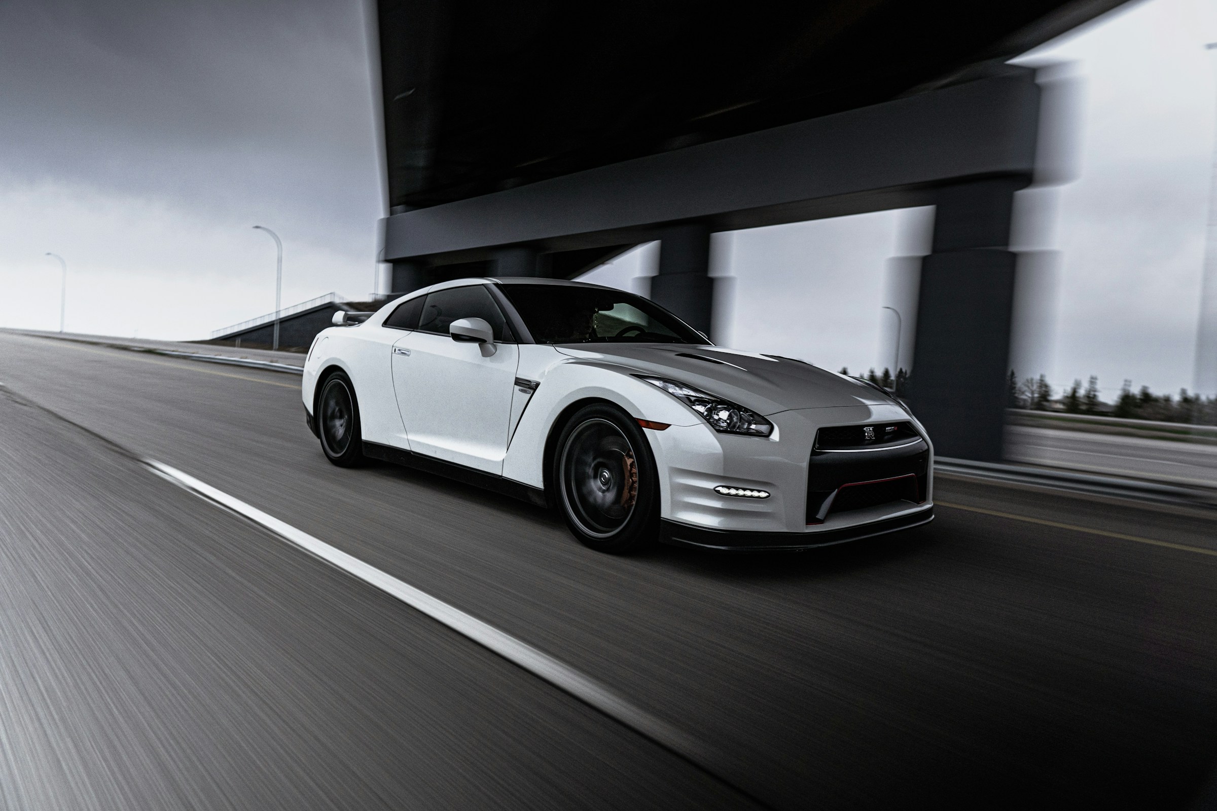 White Nissan GT-R R35 at speed under a highway overpass