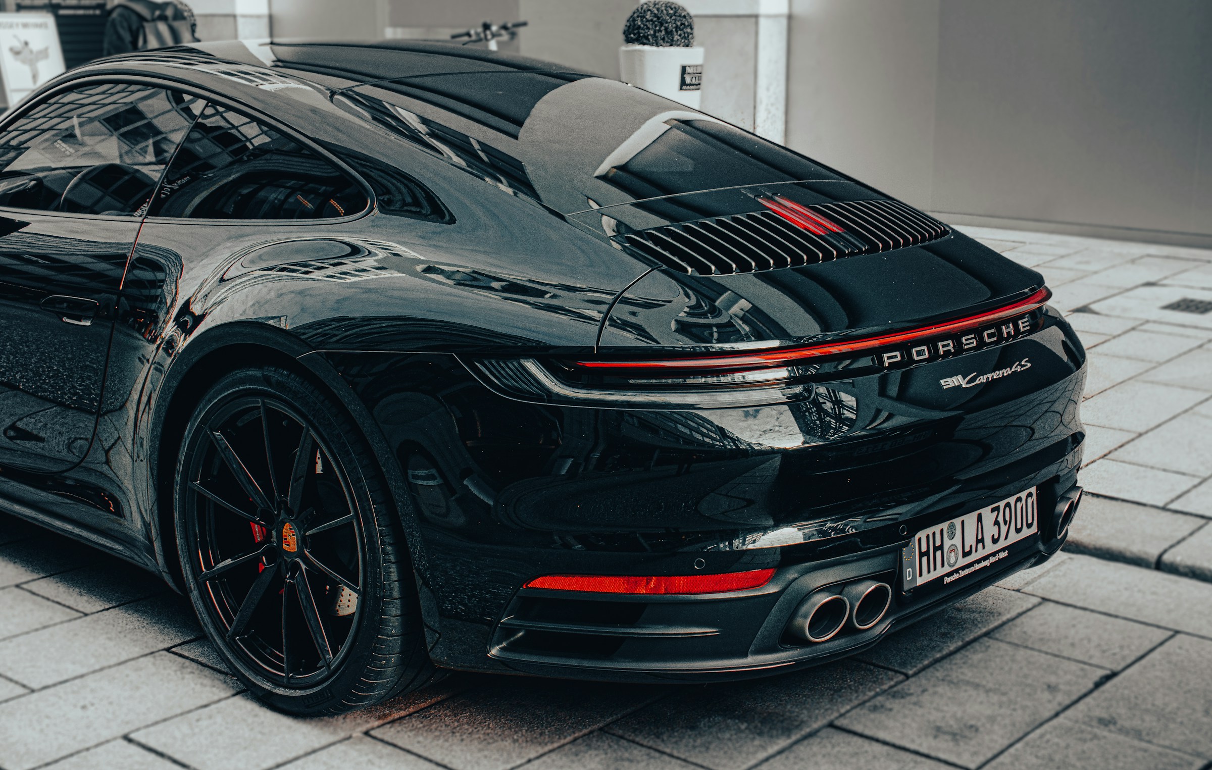 Black Porsche 911 Carrera 4S (992) rear three-quarter view on a cobbled street